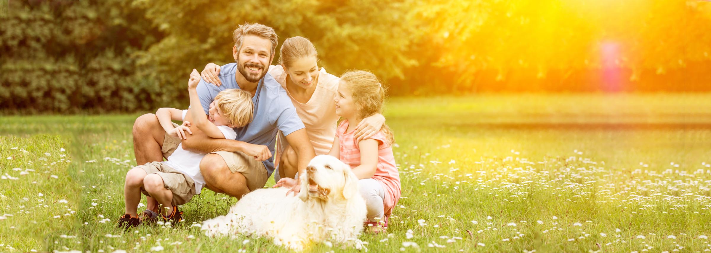 A happy family and their dog relaxing in a sunny park -labonteins.com