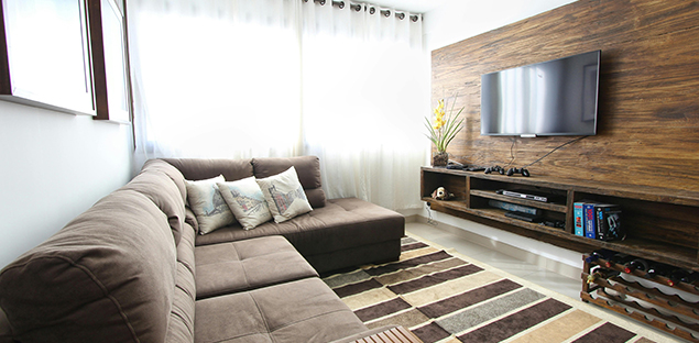A modern living room features a large brown sectional sofa, a striped rug, and a flat-screen TV mounted on a rustic wood-paneled wall - labonteins.com